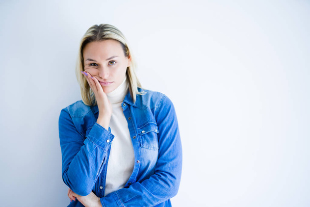 Young beautiful woman wearing denim shirt standing over isolated white background thinking looking tired and bored with depression problems with crossed arms. - 写真・画像