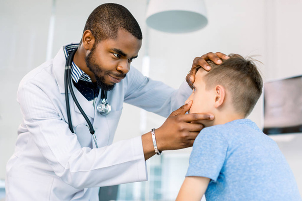 Handsome African male Doctor Examining Eyes of a little boy in medical clinic. - Foto, imagen