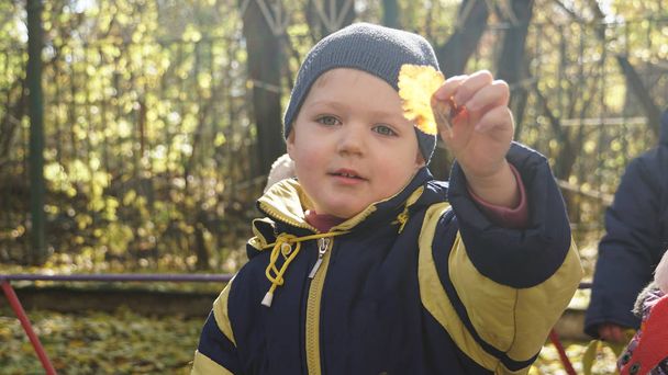Piccolo bambino sorridente con foglia di lievito nel giardino d'infanzia in autunno
 - Foto, immagini