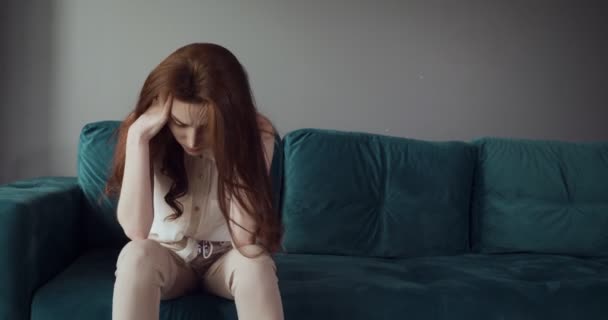 Redhead tired woman falling on sofa at home with a headache. - Video, Çekim