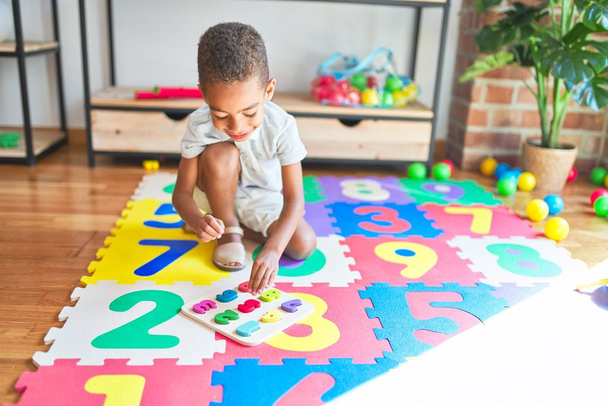 Beau bambin afro-américain jouer avec le jeu de mathématiques en utilisant des chiffres à la maternelle
 - Photo, image