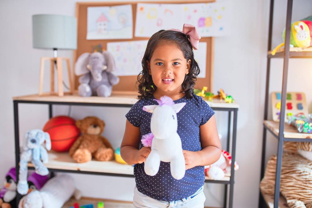 Hermosa niña sosteniendo linda muñeca unicornio en el jardín de infantes
 - Foto, imagen