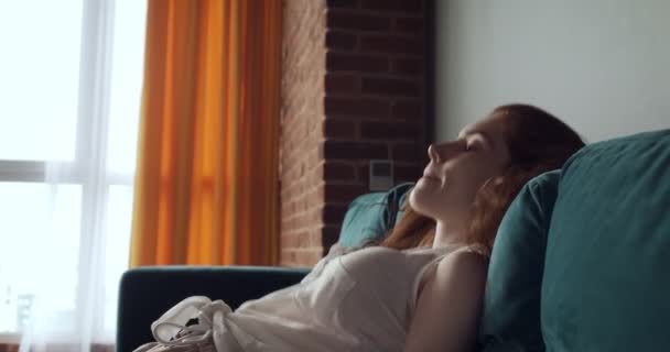Punapää väsynyt nainen putoaa sohvalla kotona päänsärky
. - Materiaali, video