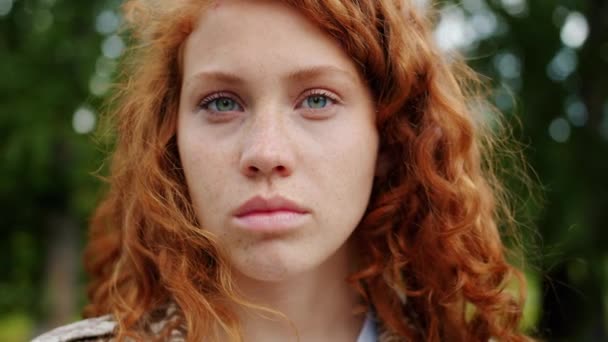 Close-up of beautiful redhead teenager looking at camera with serious face - Video