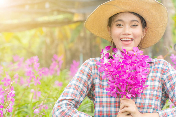 Een vrouw tuinman draagt een plaid shirt dragen van een hoed houdt  - Foto, afbeelding