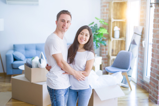 Joven hermosa pareja abrazándose en el nuevo hogar alrededor de cajas de cartón
 - Foto, imagen