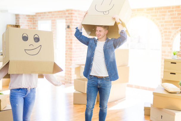 Пара веселится в новой квартире в коробках со смешными лицами над головой
 - Фото, изображение