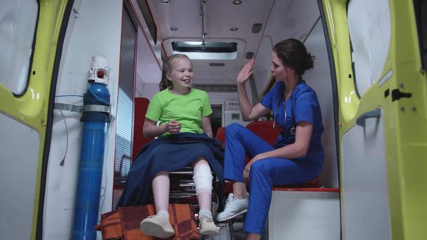 Verpleegster en ziek meisje in ambulance auto. - Foto, afbeelding