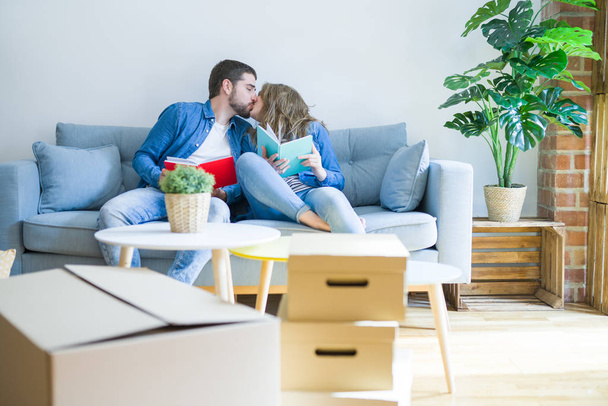 Молода пара розслабляється на дивані, читаючи книгу, роблячи перерву для переїзду в новий будинок
 - Фото, зображення