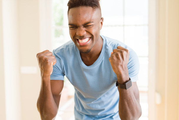 Hombre afroamericano gritando muy emocionado y celebrando el éxito y la victoria, sonriendo feliz y alegre
 - Foto, imagen