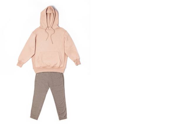 Female peach pink sweatshirt with pocket and hood, pants in classic pattern isolated on white background. Fashionable women's clothing, hoody, casual youth style, sports. Autumn fashion - 写真・画像