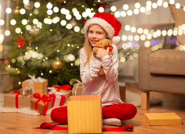 smiling girl in santa hat with christmas gift - Fotó, kép