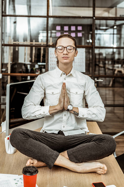 Peaceful young office worker sitting in yoga pose - Valokuva, kuva