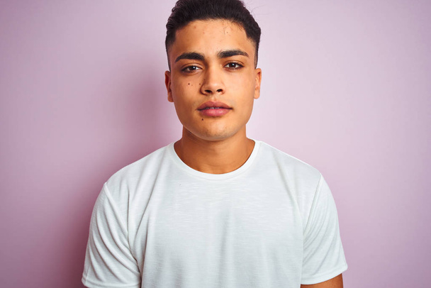 Young brazilian man wearing t-shirt standing over isolated pink background with a confident expression on smart face thinking serious - Photo, Image