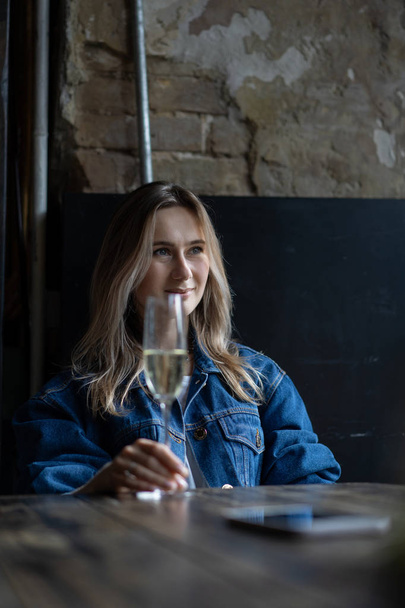 Young beautiful woman in a cafe, a woman drinking champagne in a cafe and talking. - Fotografie, Obrázek