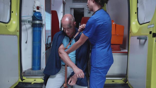 Mann mit Sauerstoffmaske sitzt nachts mit Krankenschwester im Krankenwagen. - Foto, Bild