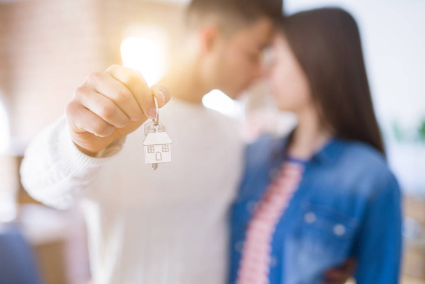 Joven pareja asiática sosteniendo las llaves de la nueva casa, sonriendo feliz y emocionado de moverse a un nuevo apartamento
 - Foto, imagen