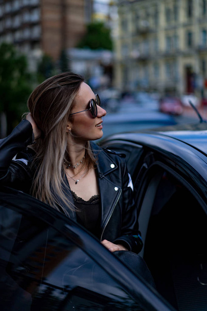 Young beautiful woman sits in a car - Fotografie, Obrázek