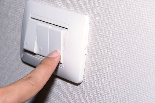Man hand is turning on or off electrical light switch. - Foto, imagen