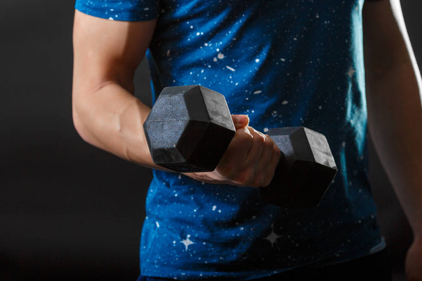 A part of mans torso, wear blue t-shirt with gymnastic dumbbell in right hand - Zdjęcie, obraz