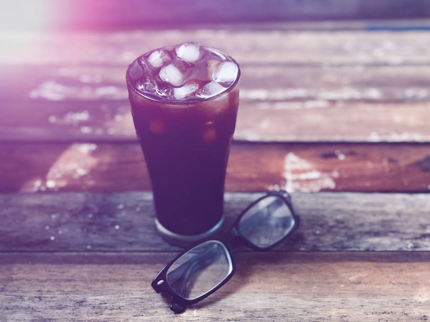 古い木のガラスと眼鏡で氷のコーヒー,レンズフレアと.素朴な静物と暗い背景,薄暗い光.夏の冷たい飲み物,あなたのテキストデザインのためのスペースと,ヴィンテージトーン,選択的な焦点.  - 写真・画像