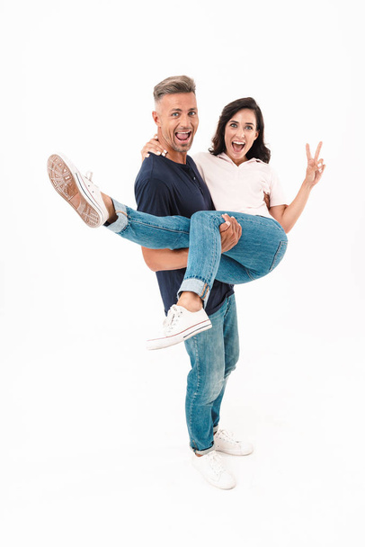 Positive adult loving couple isolated over white wall background having fun. - Foto, afbeelding