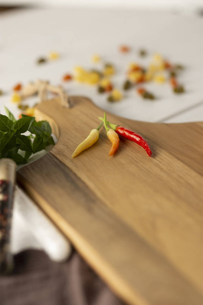 Rode Chili Pepers, oranje en geel op houten snijplank. - Foto, afbeelding