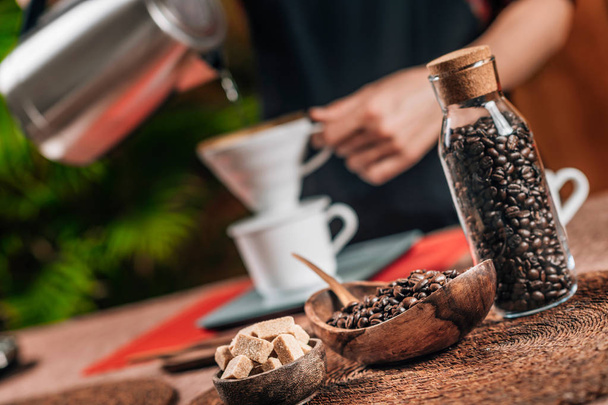 Капельный кофе. Бариста наливает кипящую воду из чайника в ручной капельный кофейник
 - Фото, изображение