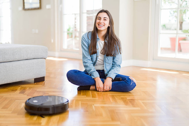 Young woman using automatic vacuum cleaner to clean the floor, controling machine housework robot - Foto, Bild