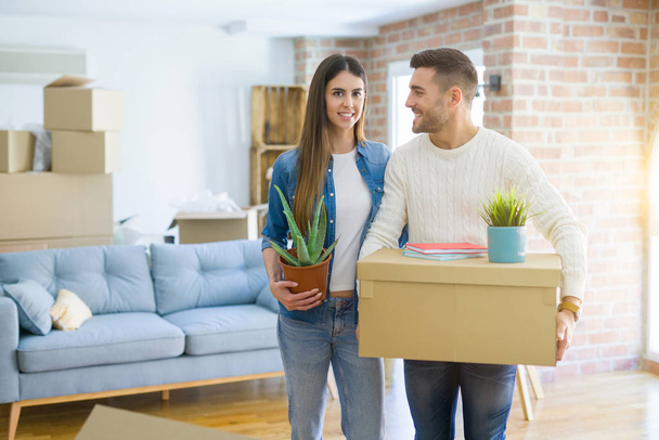 Красива молода пара переїжджає в новий будинок, усміхнений щасливий тримає картонні коробки в новій квартирі
 - Фото, зображення