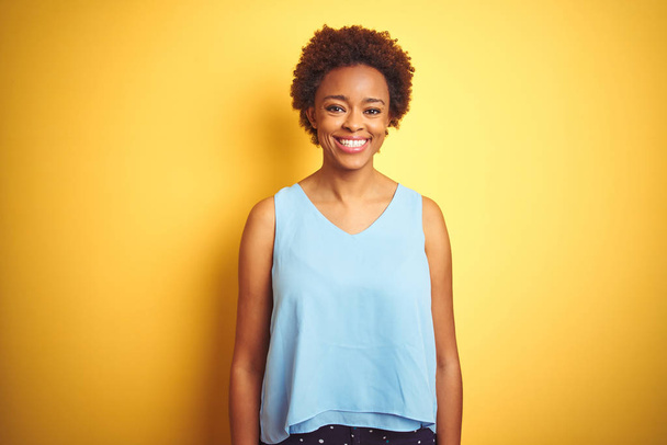 Красивая африканская американка в элегантной рубашке на изолированном желтом фоне со счастливой и прохладной улыбкой на лице. Счастливчик
. - Фото, изображение