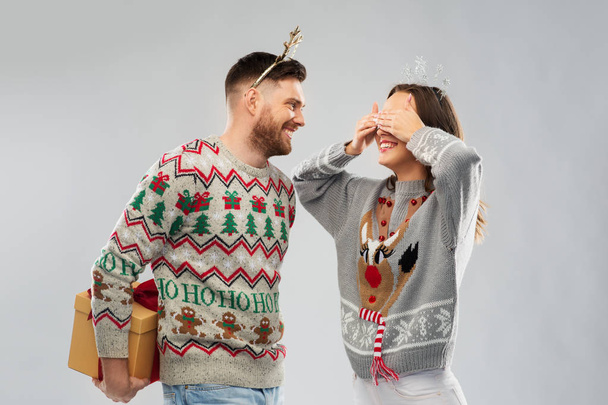 happy couple in christmas sweaters with gift box - Zdjęcie, obraz
