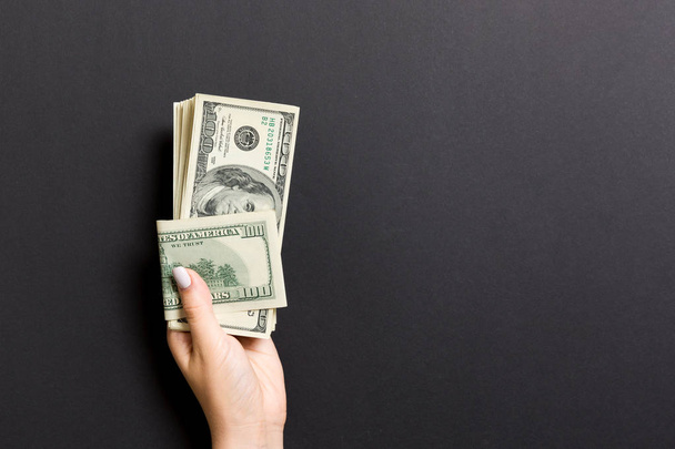 Die weibliche Hand hält ein Bündel Hundert-Dollar-Banknoten auf buntem Hintergrund. Gehalts- und Lohnkonzept mit Kopierraum - Foto, Bild