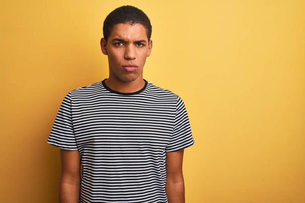 Young handsome arab man wearing navy striped t-shirt over isolated yellow background skeptic and nervous, frowning upset because of problem. Negative person. - Foto, imagen