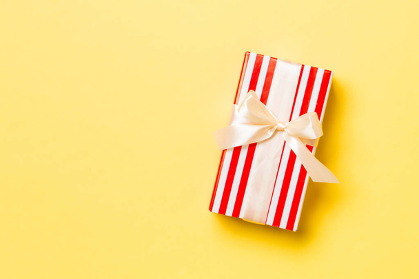 verpackte Weihnachten oder andere Feiertage handgemachtes Geschenk in Papier mit gelbem Band auf gelbem Hintergrund. Geschenkschachtel, Geschenkdekoration auf farbigem Tisch, Draufsicht mit Kopierraum - Foto, Bild