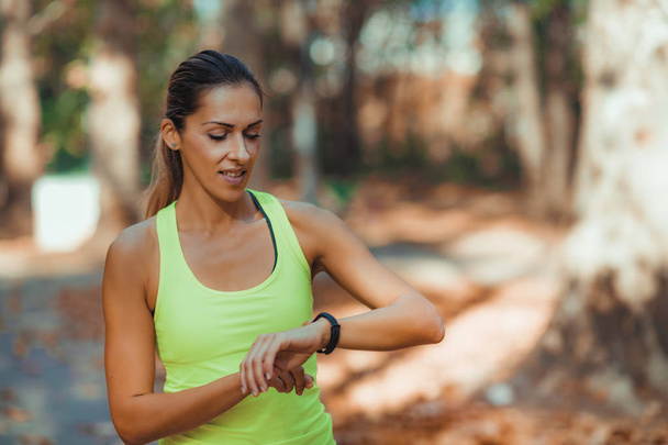Vrouw controleert de voortgang op Smart Watch na outdoor training - Foto, afbeelding