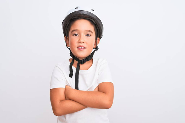 Όμορφο αγόρι φορώντας ποδήλατο κράνος ασφαλείας στέκεται πάνω από απομονωμένο λευκό φόντο χαρούμενο πρόσωπο χαμογελώντας με σταυρωμένα χέρια κοιτάζοντας την κάμερα. Θετικό πρόσωπο. - Φωτογραφία, εικόνα