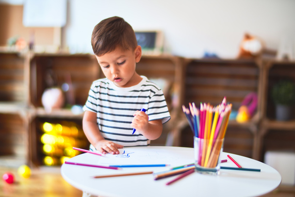 Красивый мальчик рисовал милые рисунки цветными карандашами в детском саду
 - Фото, изображение