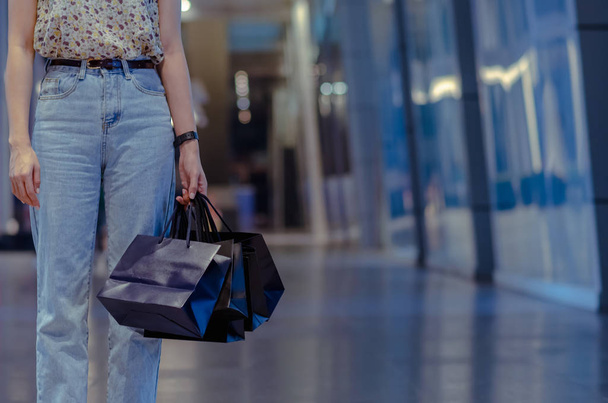 Woman holding shopping bags with shopping mall background. Black Friday sale concept. - Photo, Image