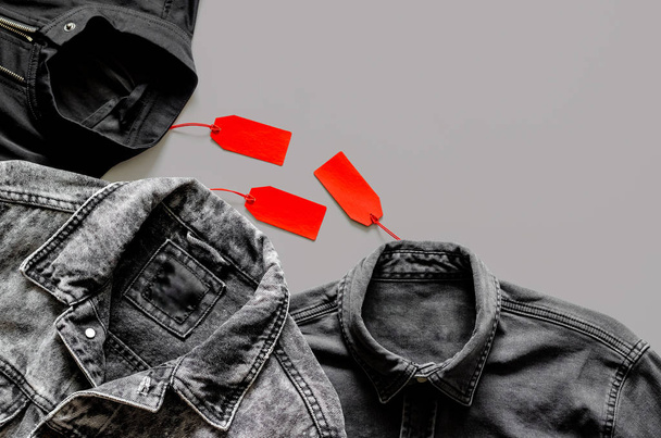 Επίπεδη βάση ανδρών μαύρα ρούχα με κόκκινες ετικέτες τιμή στο γκρι φόντο για την μαύρη Παρασκευή αγορά πώλησης ιδέα. - Φωτογραφία, εικόνα