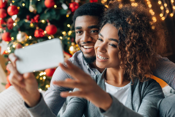 Young loving couple making selfie with Christmas tree - Foto, Imagen