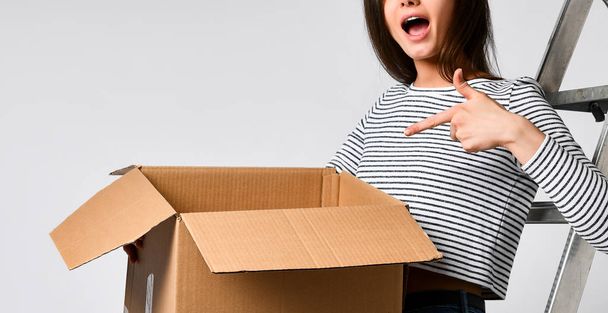 Delivery, relocation and unpacking. Smiling young woman holding cardboard box isolated on white background - Photo, image