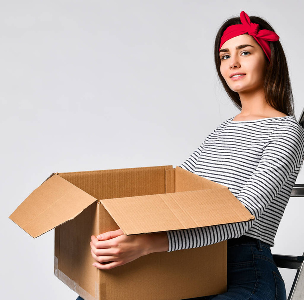 Consegna, trasferimento e disimballaggio. Sorridente giovane donna in possesso di scatola di cartone isolato su sfondo bianco
 - Foto, immagini