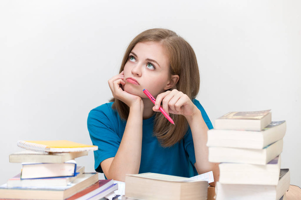 Young caucasian girl woman with many books study at school or university, looks tired, stressed or exhausted, thinking - Photo, image