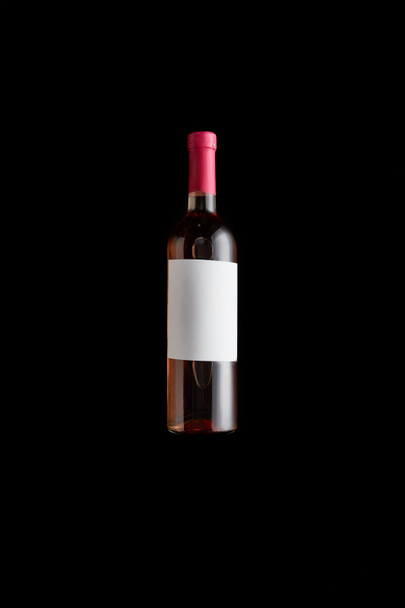 vista superior de la botella con vino rosa y etiqueta blanca en blanco aislado en negro
 - Foto, Imagen