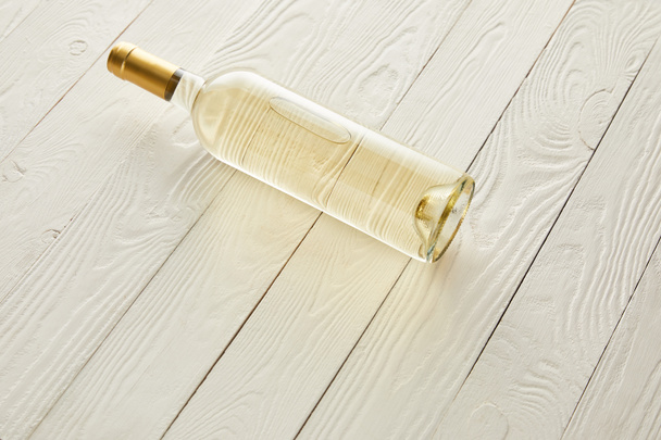 bottle with white wine on white wooden surface - Φωτογραφία, εικόνα