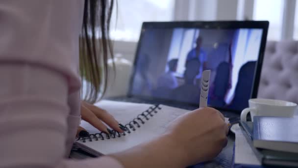 e-learn, mujer que utiliza ordenador portátil para la educación de vídeo y la discusión de trabajo a distancia haciendo notas en el cuaderno
 - Imágenes, Vídeo
