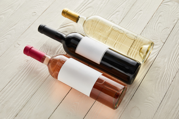 bottles with red, white and rose wine on white wooden surface - Foto, Imagem