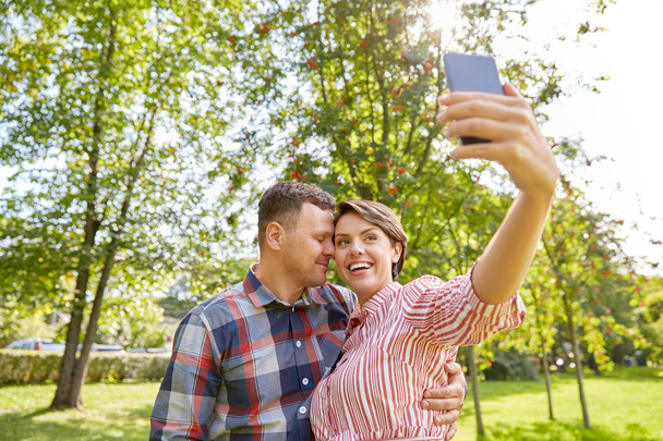 happy couple in park taking selfie by smartphone - Foto, imagen