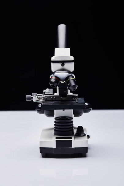 microscopio moderno sobre mesa blanca aislada sobre negro
 - Foto, Imagen